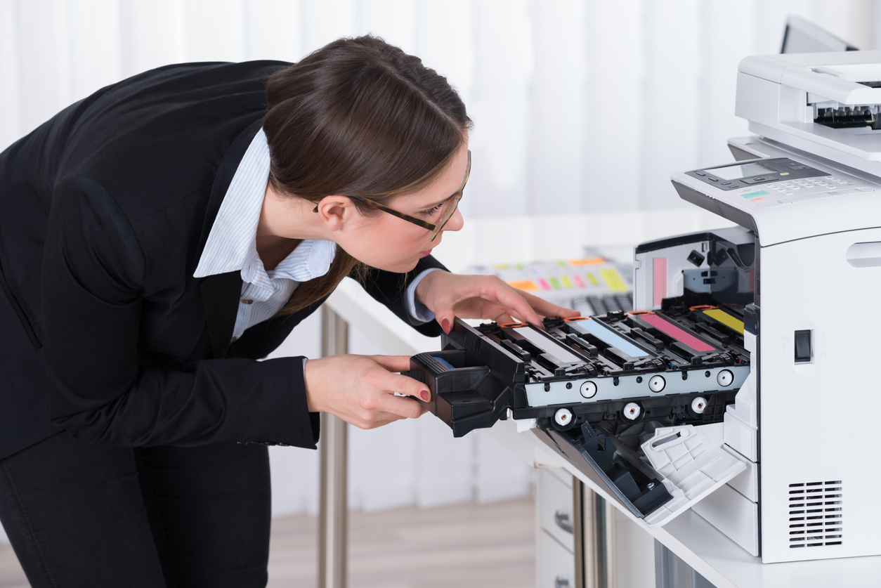 Young Businesswoman Fixing Copy Machine At Workplace